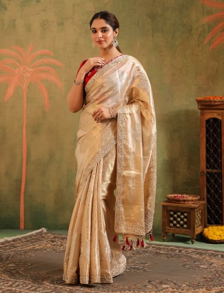 Cream silk celebration saree enhanced with a vibrant red blouse
